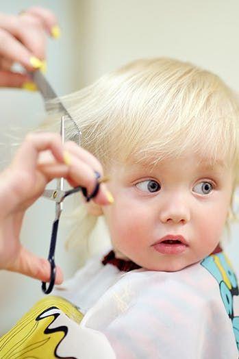 A friendly stylist cutting a young child's hair at Red Hair Hastings salon, creating a fun and comfortable experience for kids.